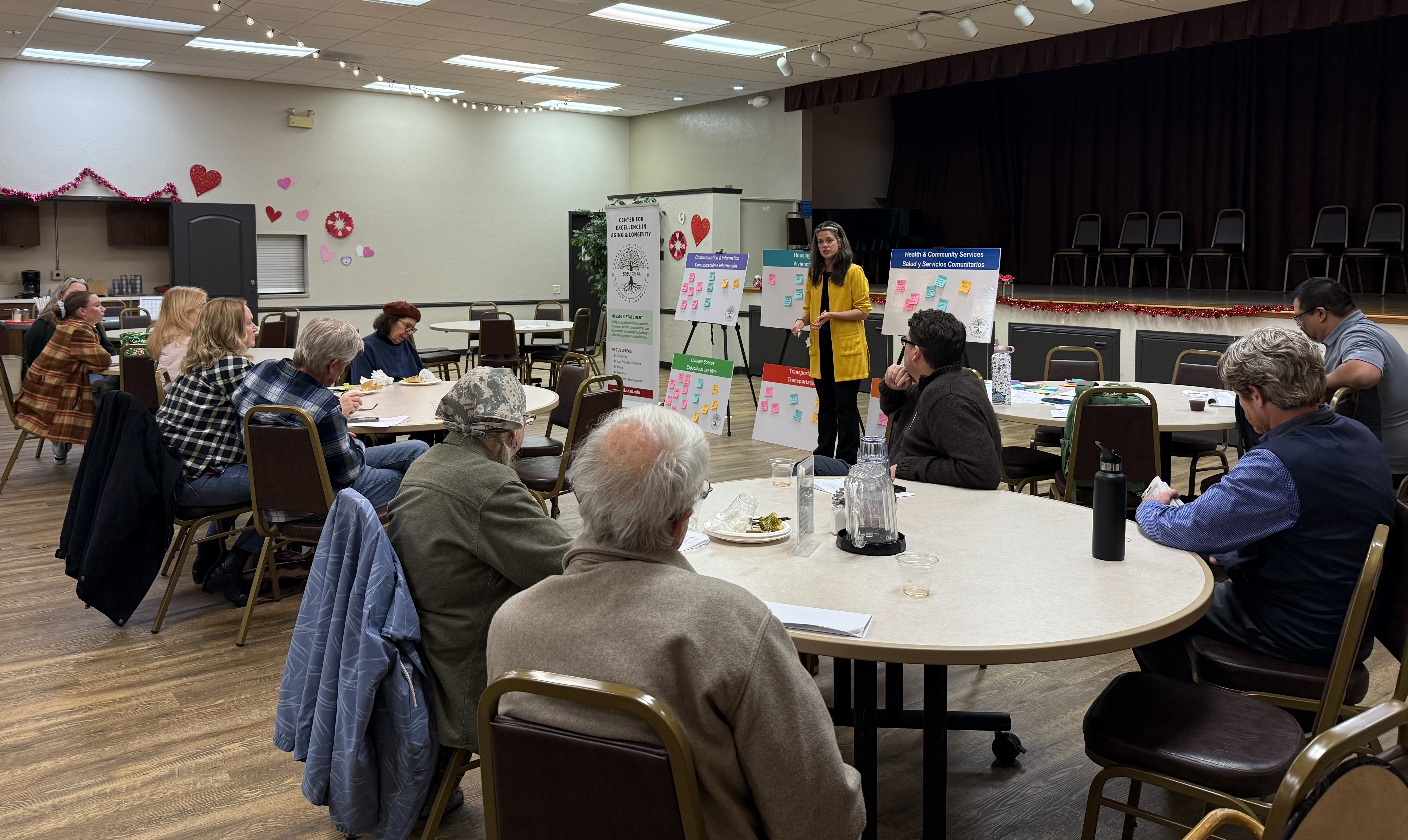Elderly people listening to a presentation around tables