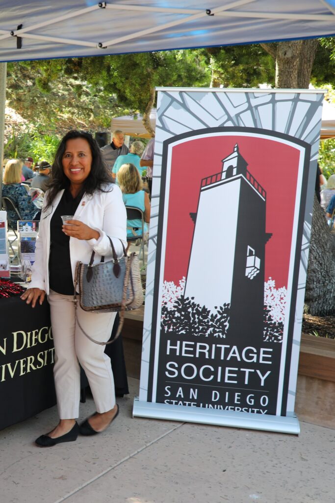 Business woman posing in front of the SDSU Heritage Society Sign