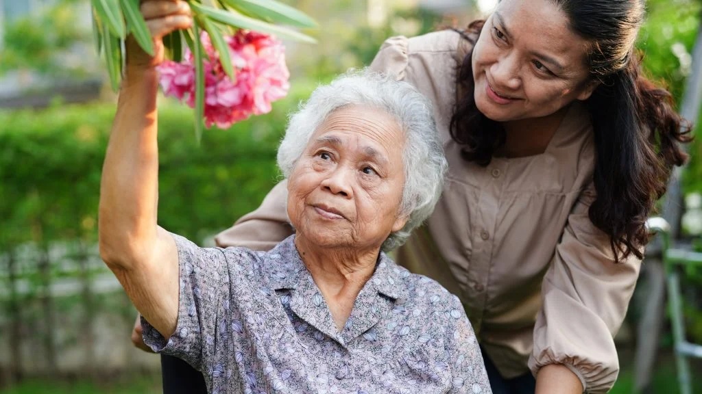 Grandmother and daughter on a walk looking at a pink flower