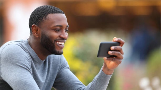 Man with black skin watching media on smart phone in a bar